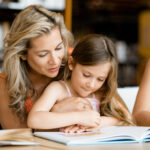 Little girls with their mother reading books in library